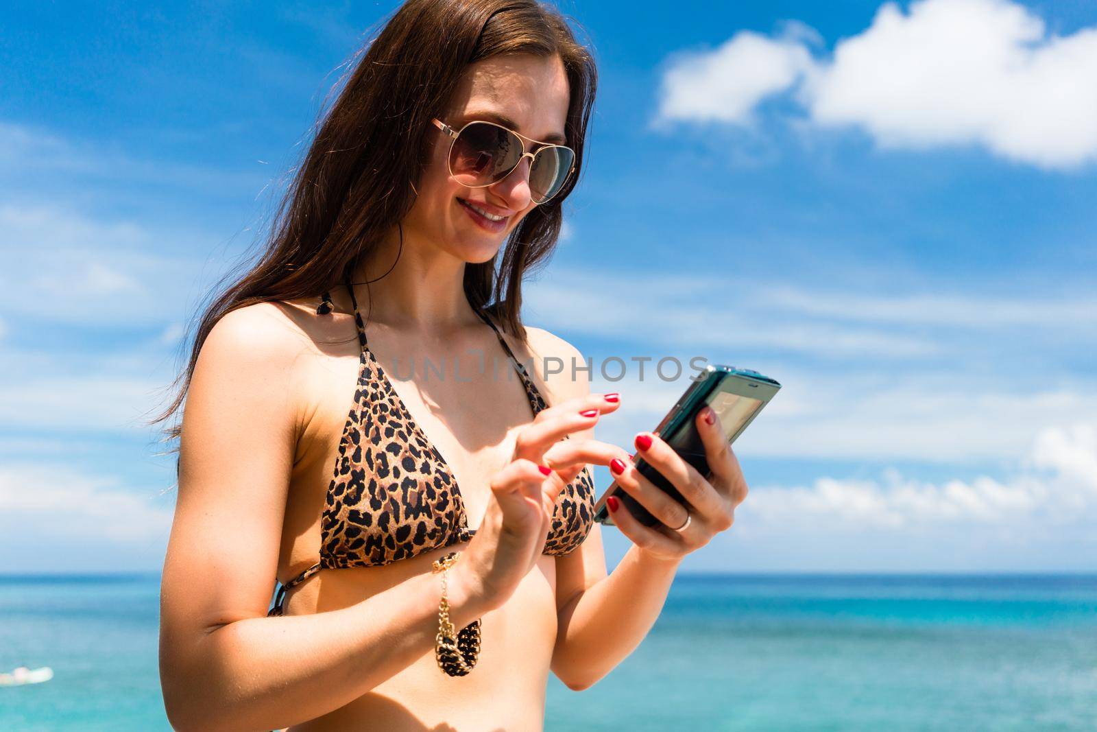 Woman on beach with phone typing text message or chatting