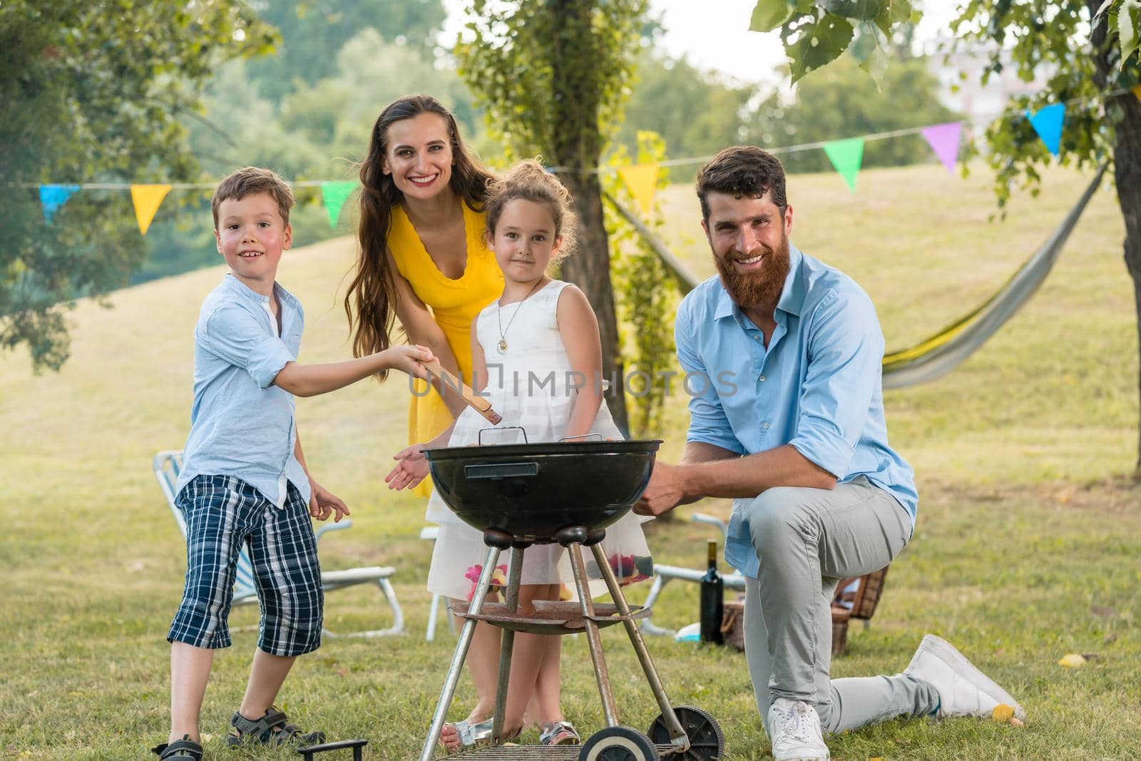 Portrait of happy family with children posing behind a barbecue by Kzenon