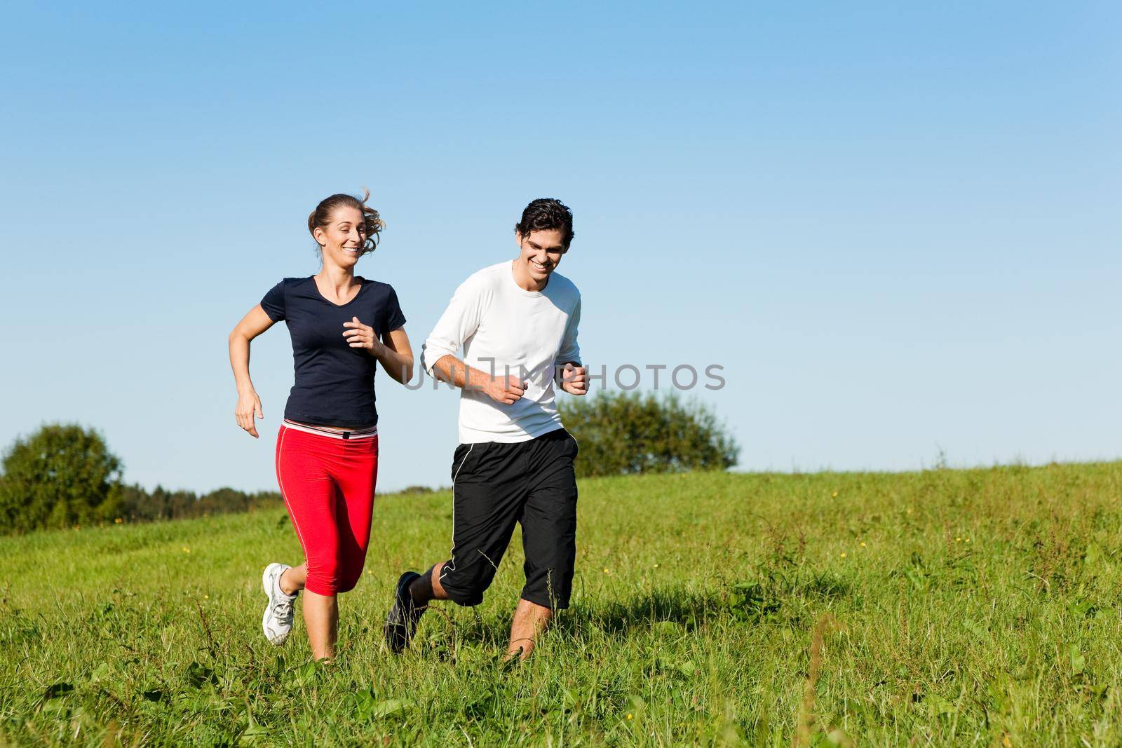 sport couple jogging an meadow in summer by Kzenon