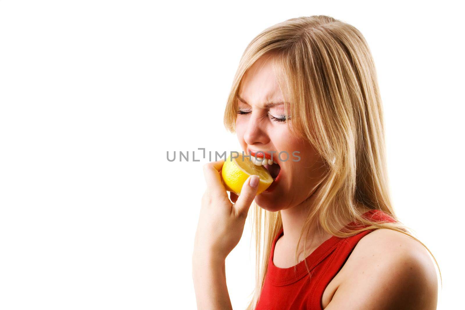 Woman having a nibble of a lemon making a grimace