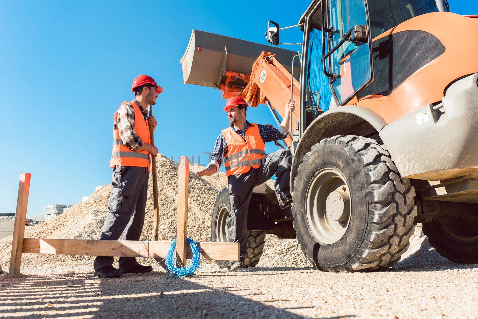 Workers on construction site discussing the use of tools by Kzenon