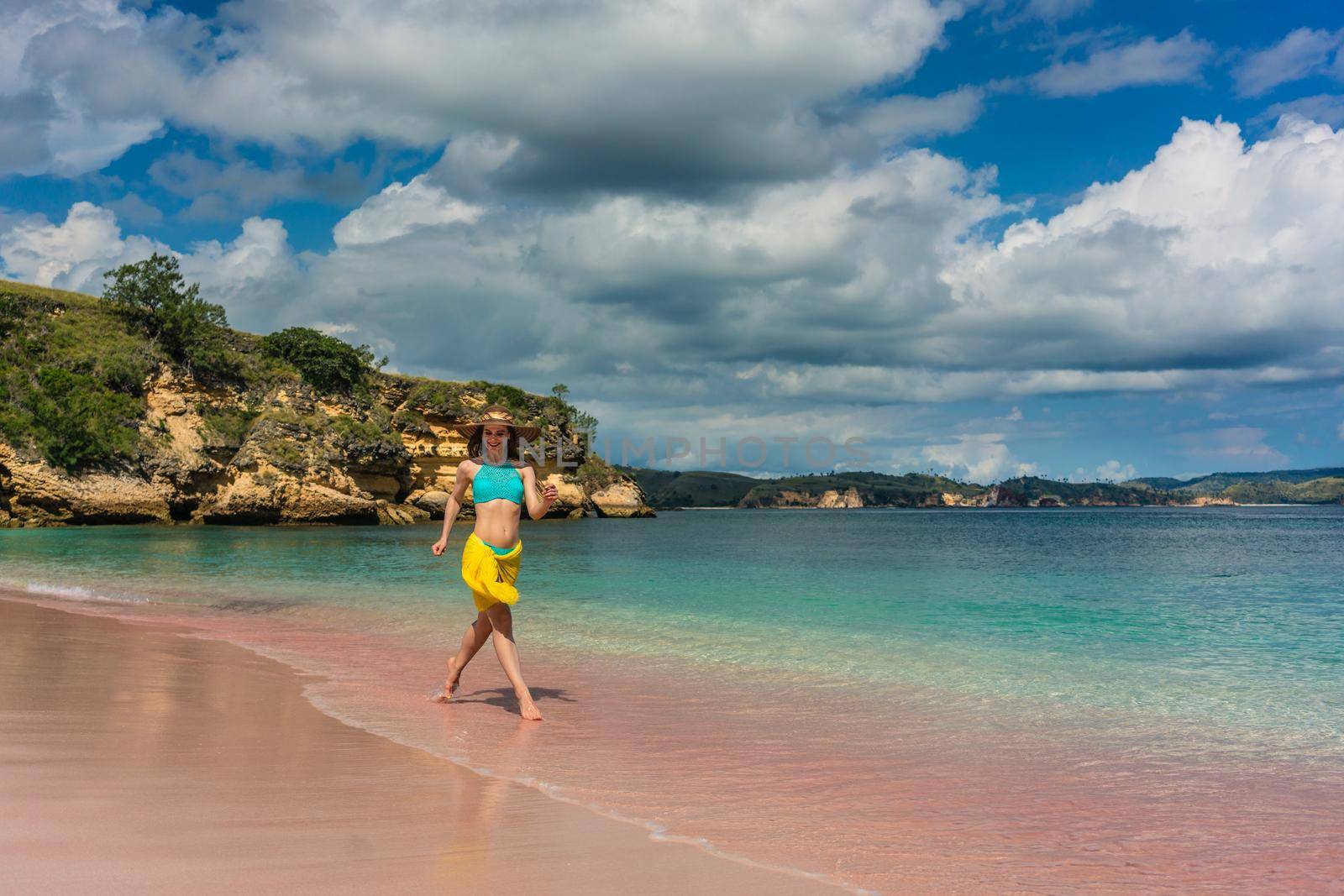 Full length of a fashionable young woman enjoying happiness and freedom while walking on a tropical beach during summer vacation in Komodo Island, Indonesia