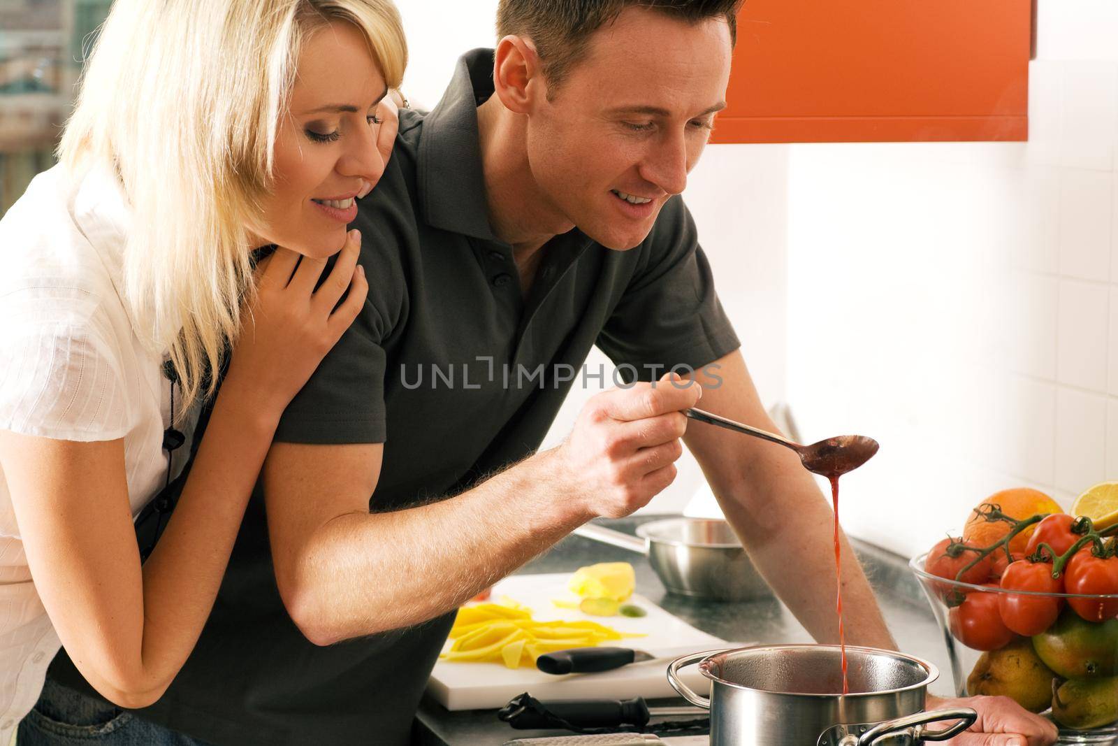 Young couple cooking (in this case: strawberry sauce for dessert)