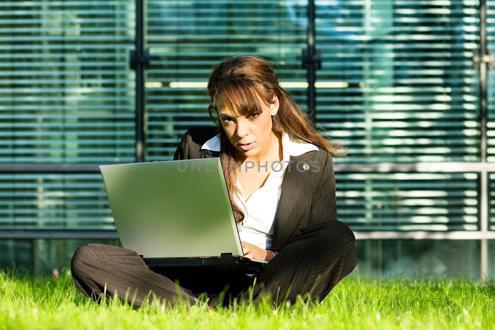 A female professional sitting with her laptop on the lawn