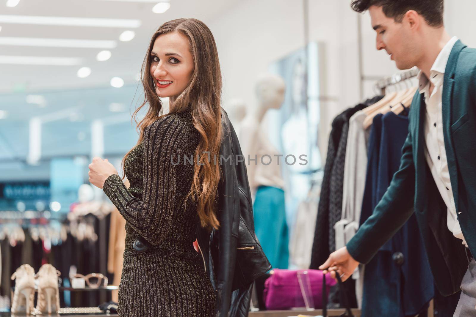 Woman trying a new leather jacket in hip fashion boutique by Kzenon