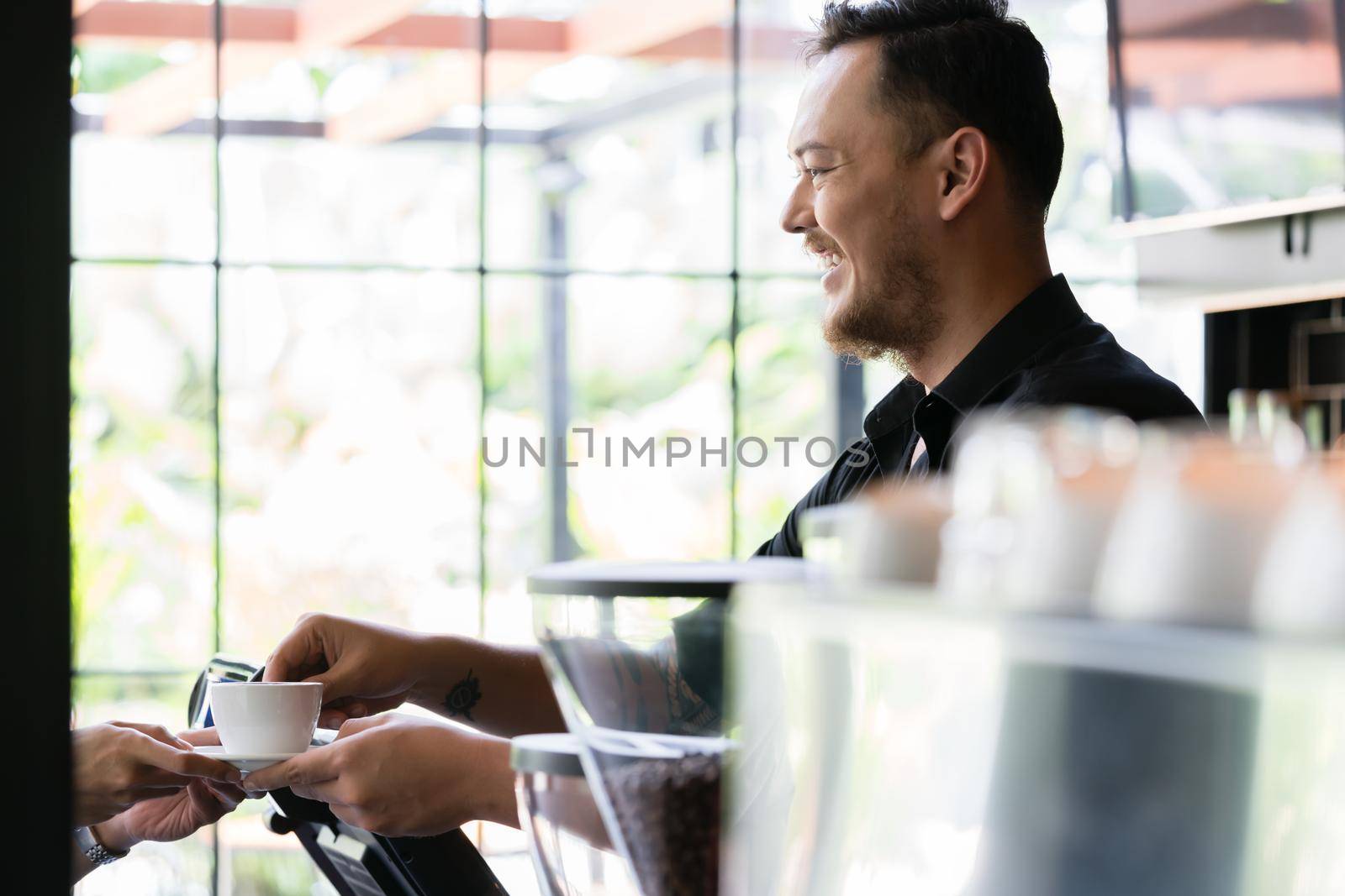 Friendly bartender serving a short espresso to a customer by Kzenon