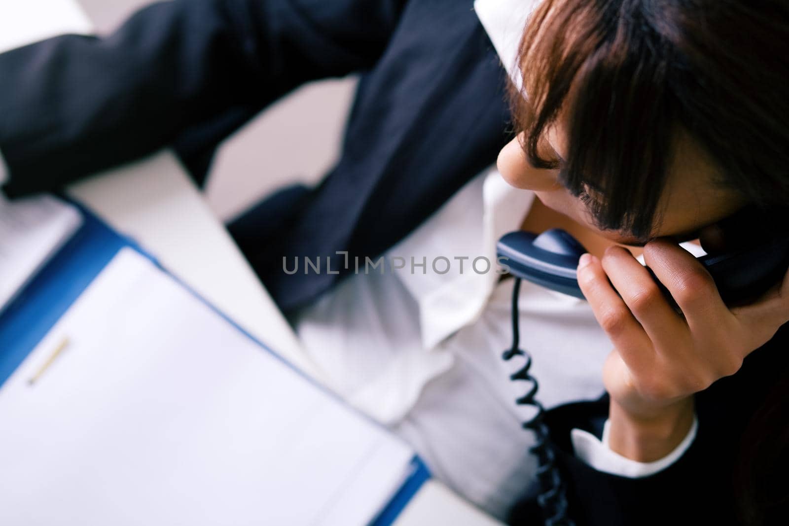 Girl in the office on the phone looking in a file