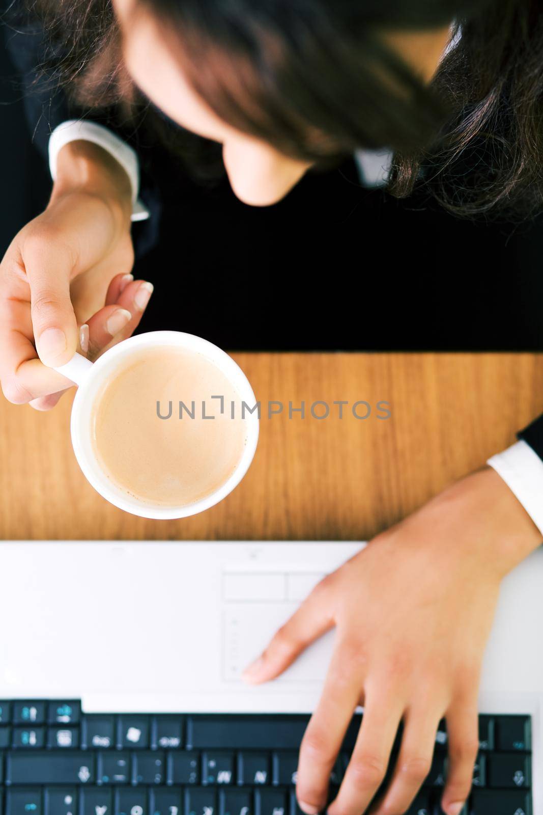 A woman (just hands) at her workplace having a double espresso (focus on hand and cup)