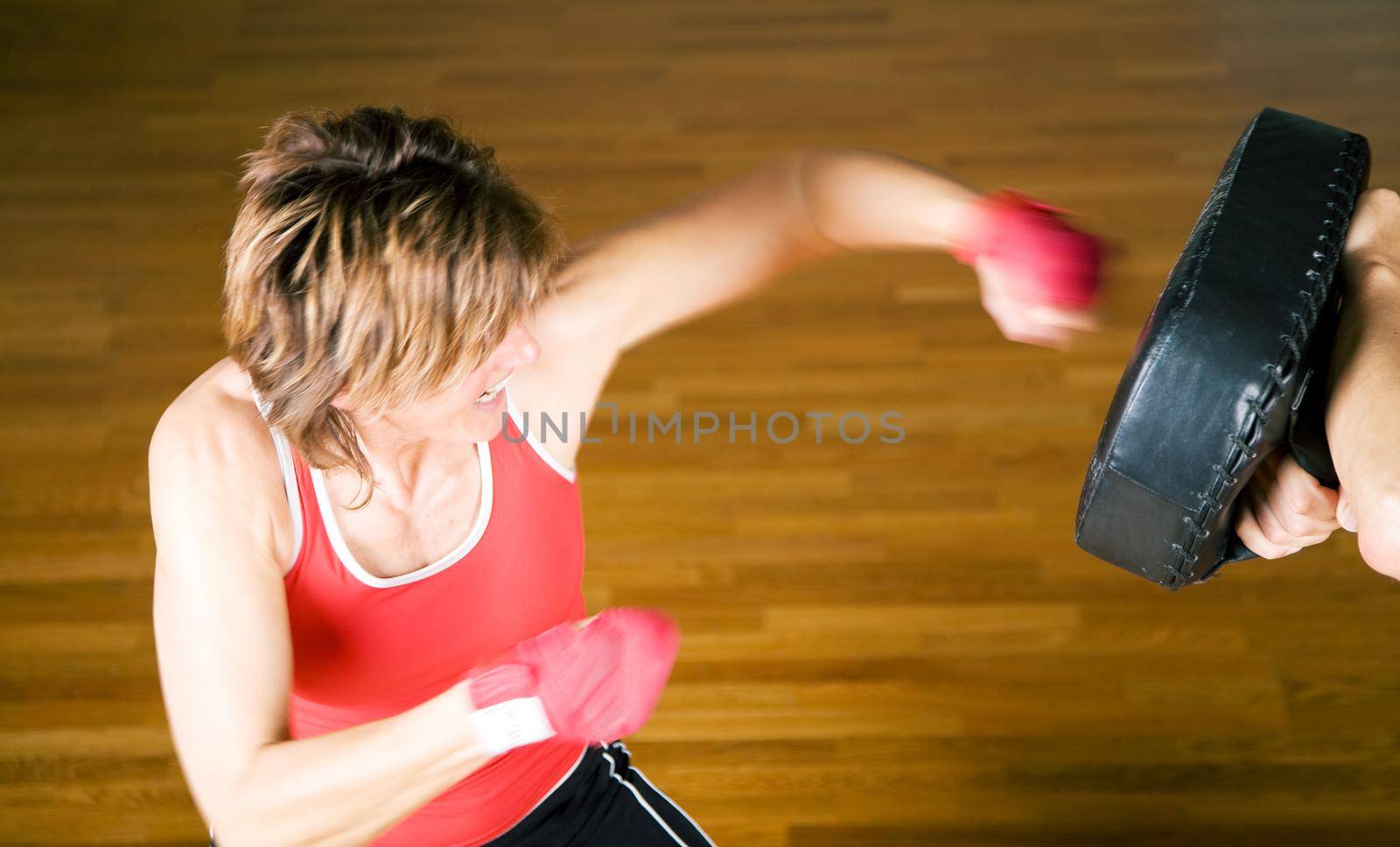Sparring session in marital arts (very dynamic picture – motion blur!), woman punching with her fist