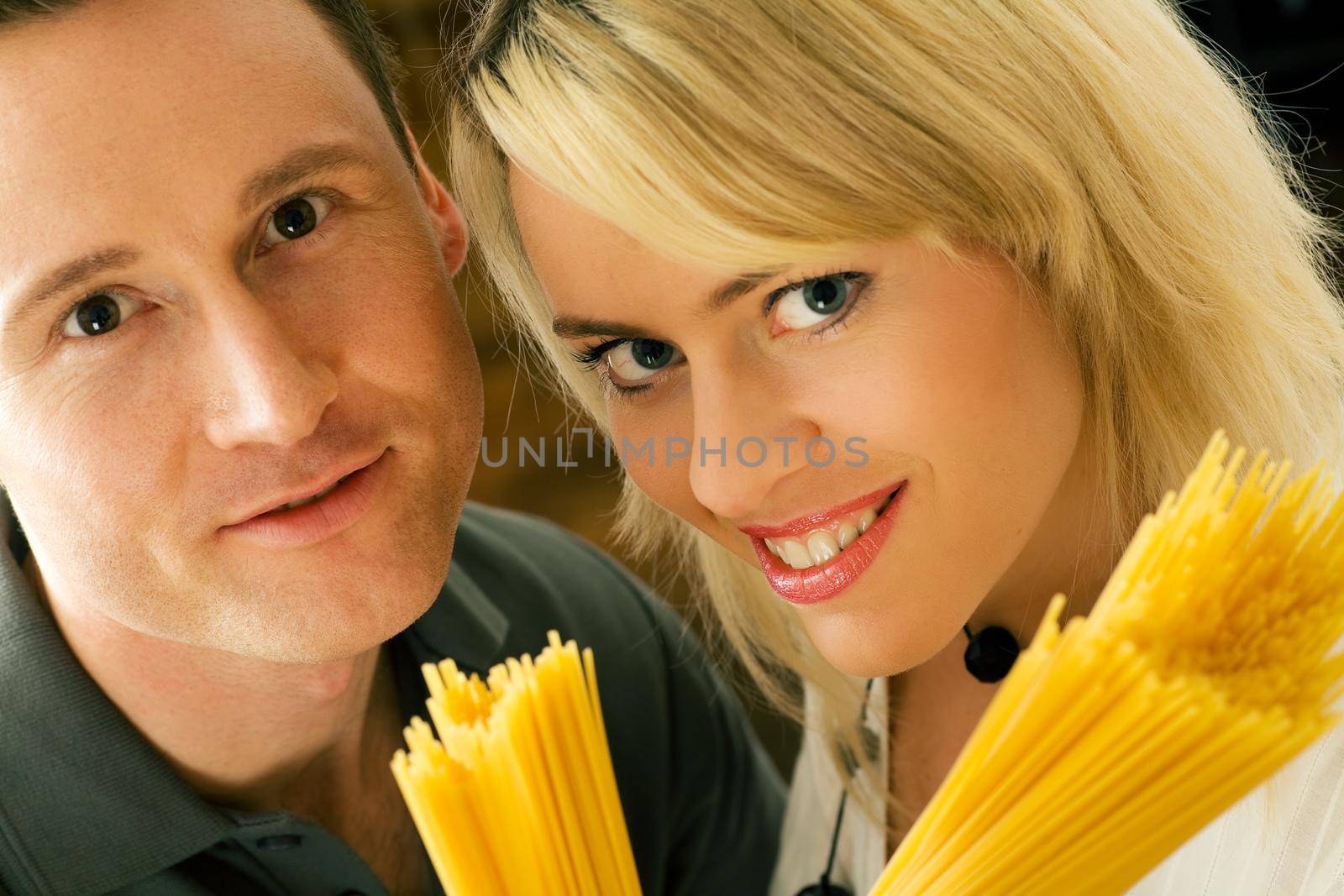 A couple with uncooked spaghetti (going to prepare them presumably)