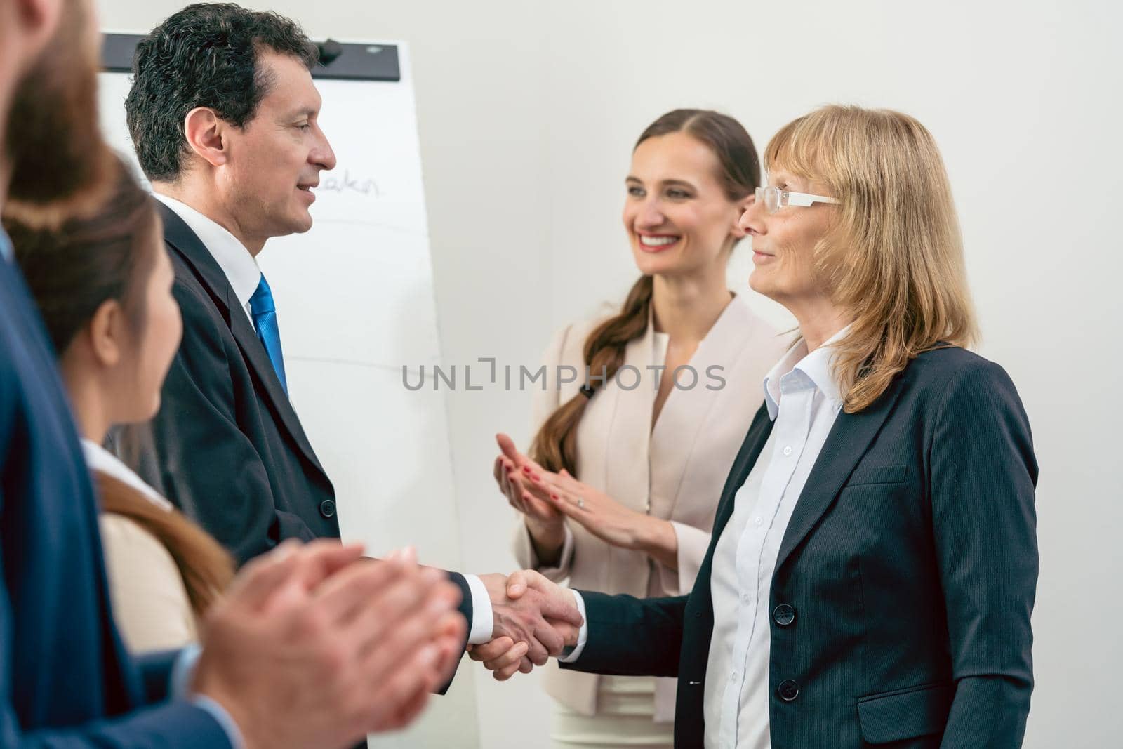 Two middle-aged business associates smiling while shaking hands by Kzenon