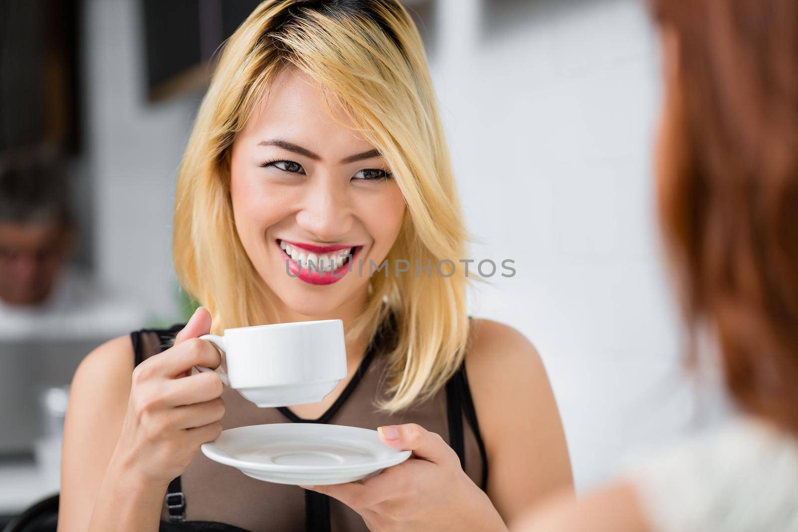 Beautiful blond Asian woman drinking coffee by Kzenon