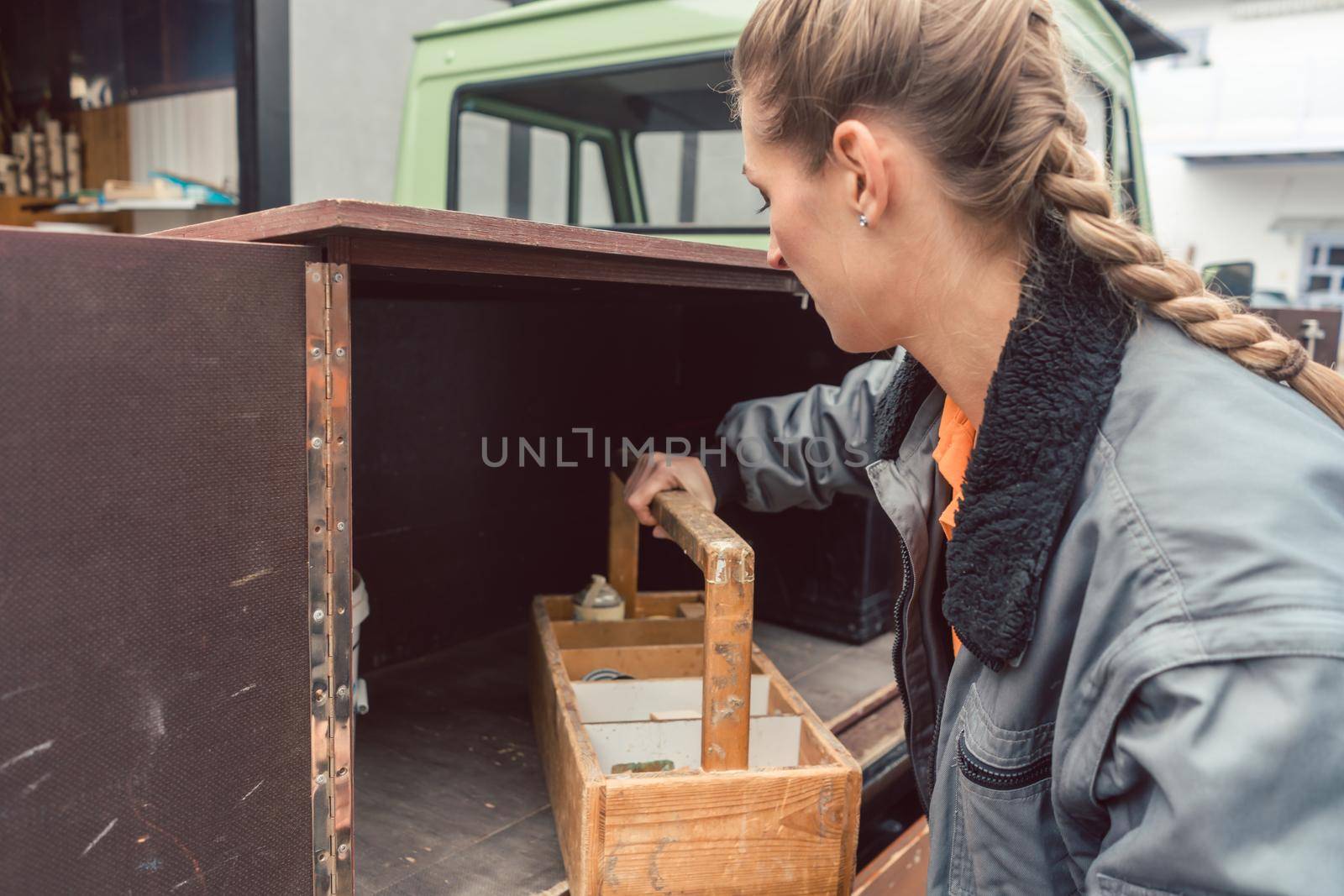 Woman carpenter loading tools in mobile workshop transporter by Kzenon