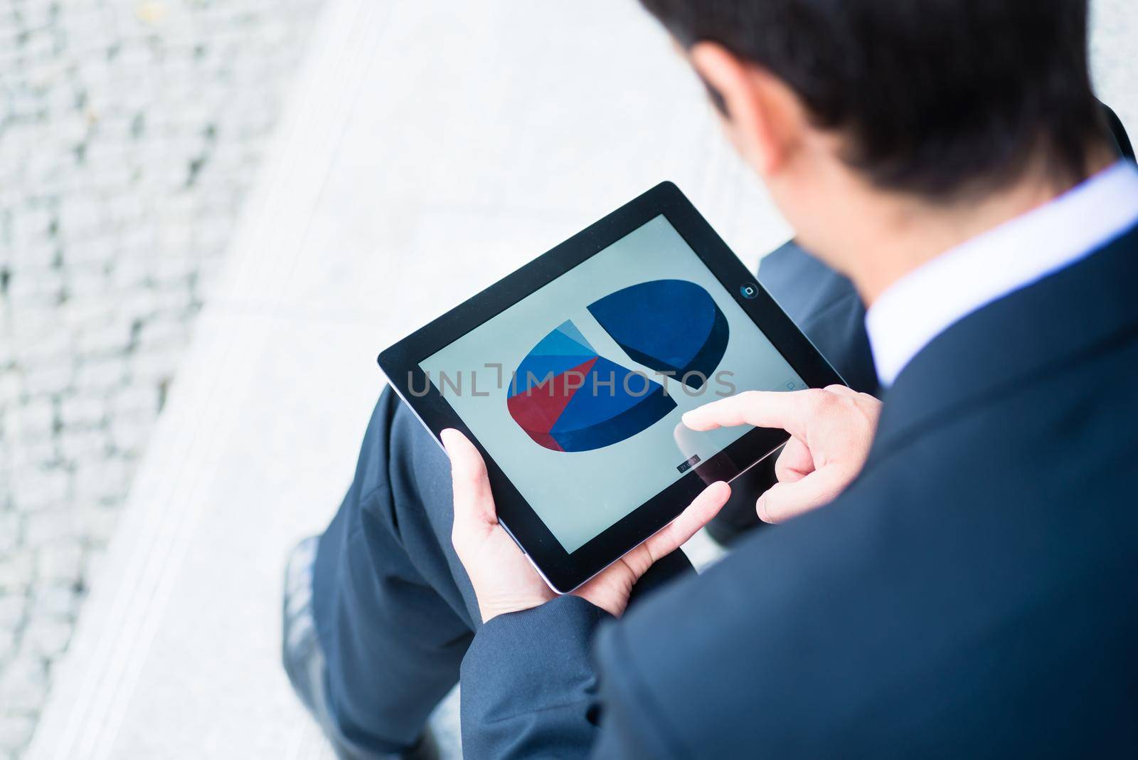 Businessman checking a pie graph on a tablet by Kzenon