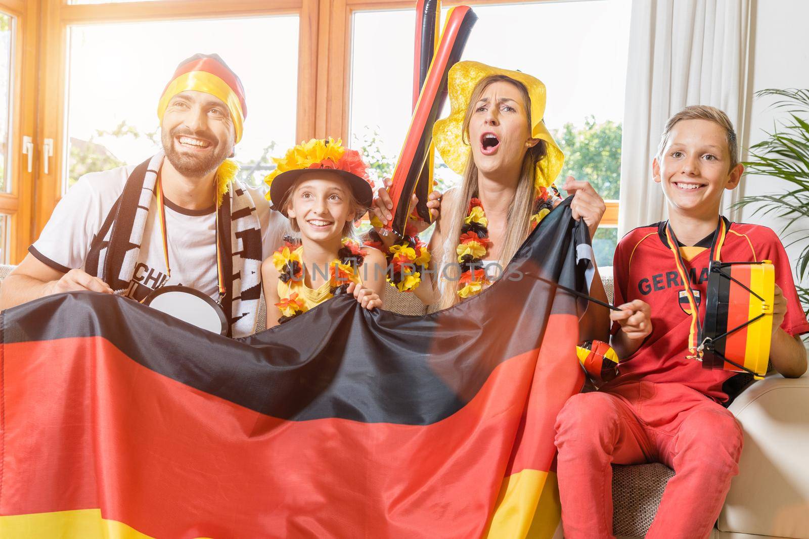 Whole family cheering for the German soccer team in front of TV by Kzenon