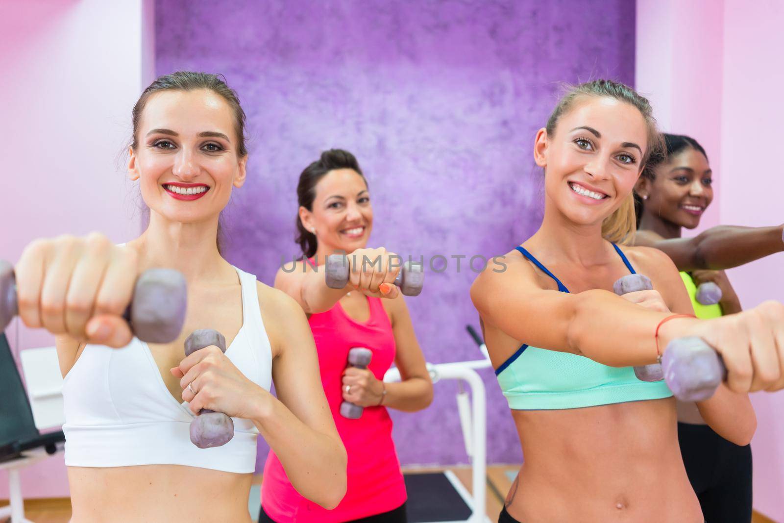 women exercising with dumbbells during group class in a contempo by Kzenon