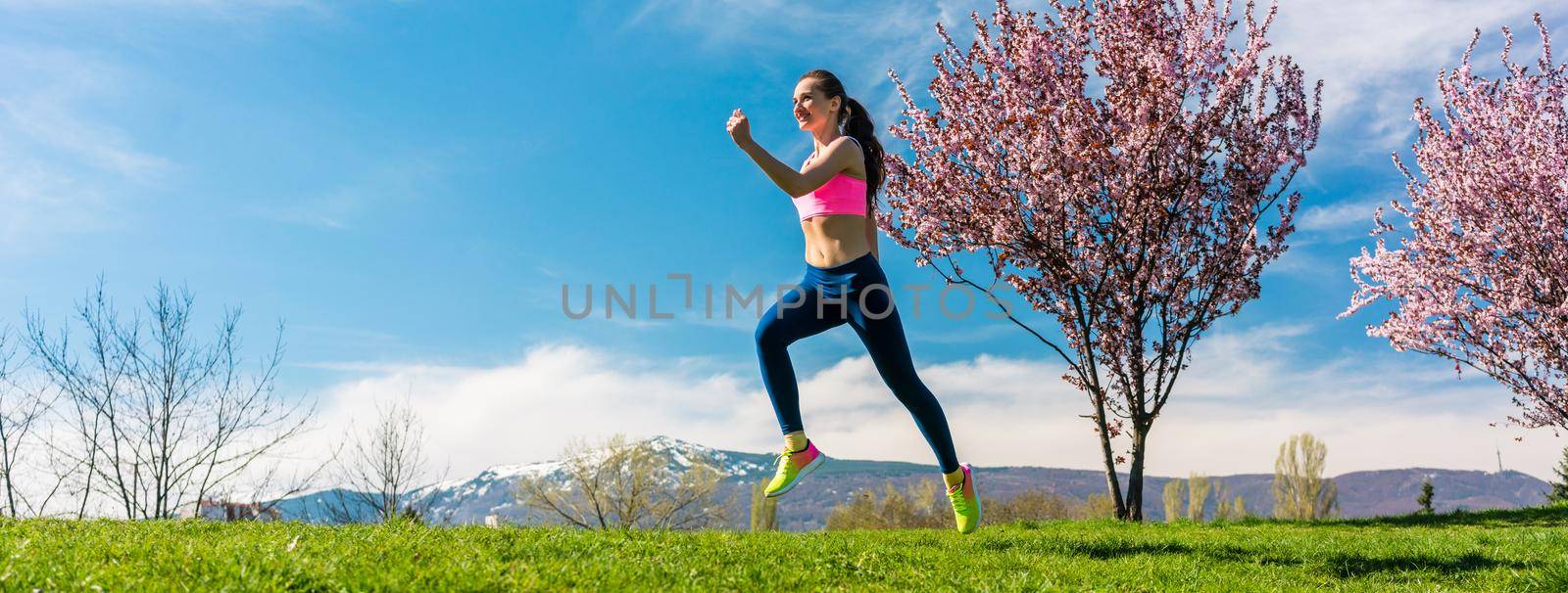 Woman sport running on hill for fitness with blossoming trees