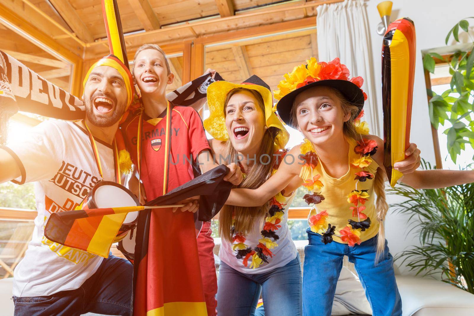 Whole family cheering for the German soccer team in front of TV by Kzenon