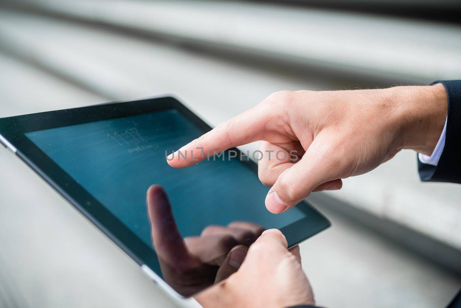 Businessman navigating on a tablet computer using his finger on the touchscreen as he surfs the internet, close up view
