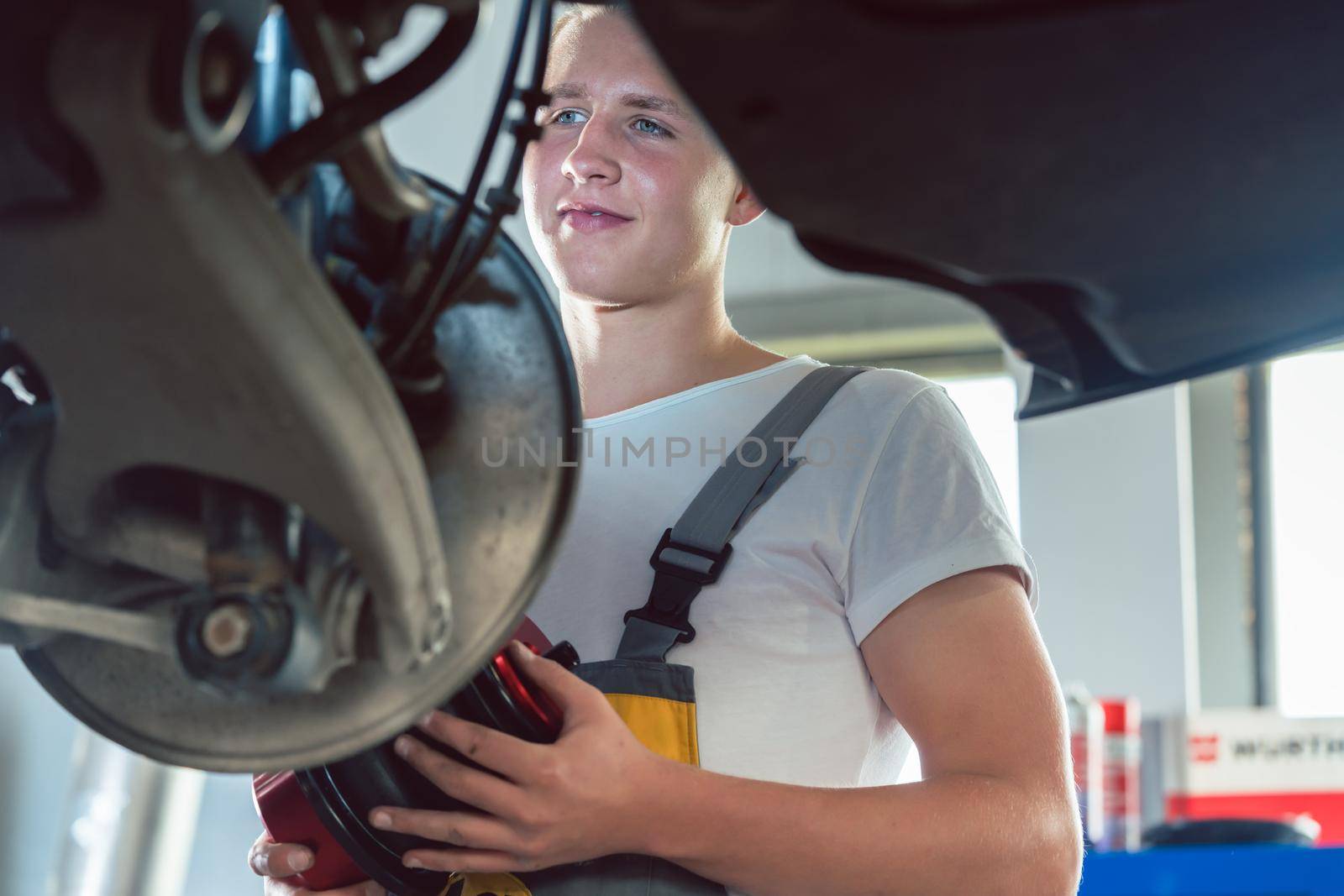 Dedicated mechanic working in a modern automobile repair shop by Kzenon