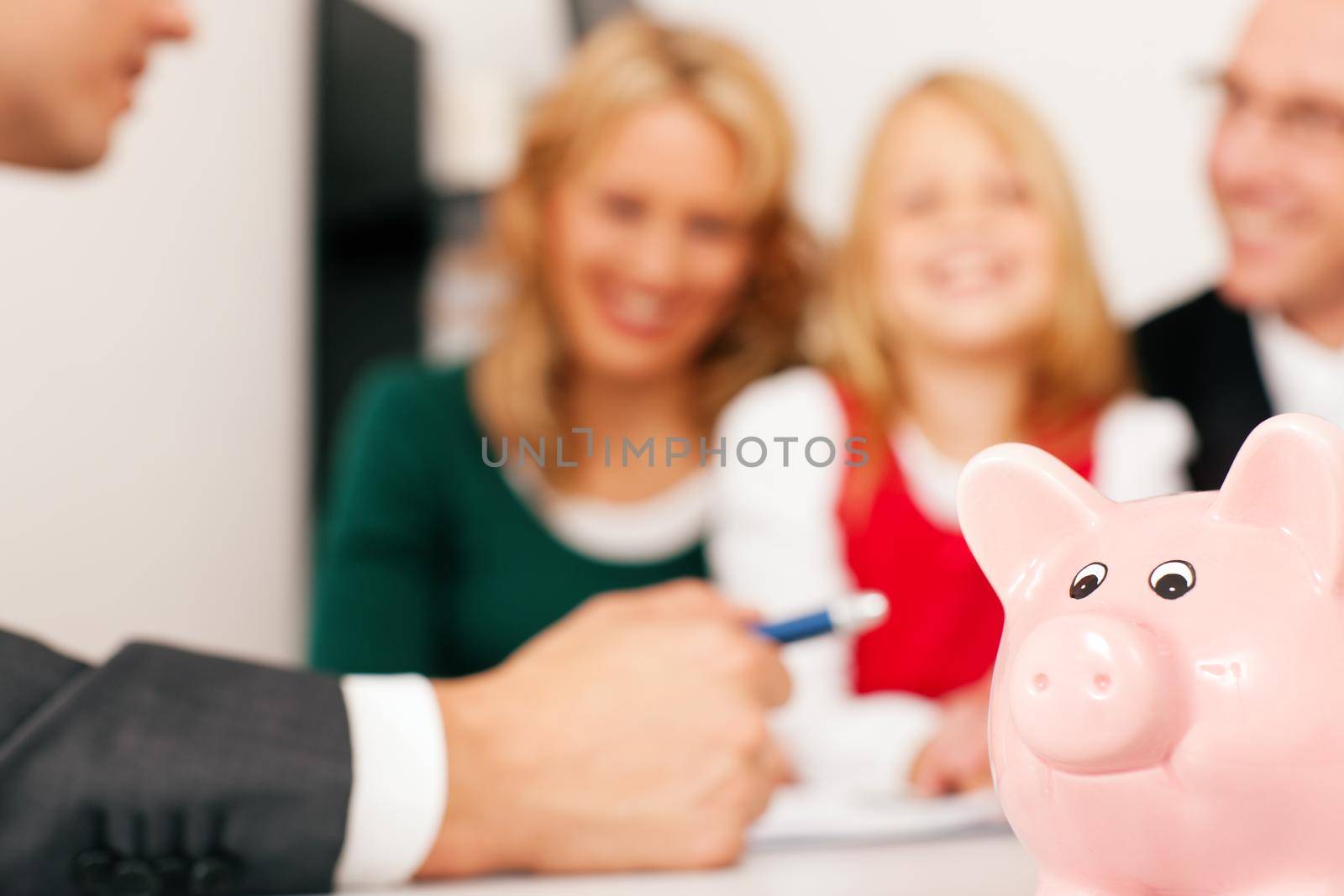 Family with their consultant (assets, money or similar) doing some financial planning - symbolized by a piggy bank in the front (focus only on piggy bank!)