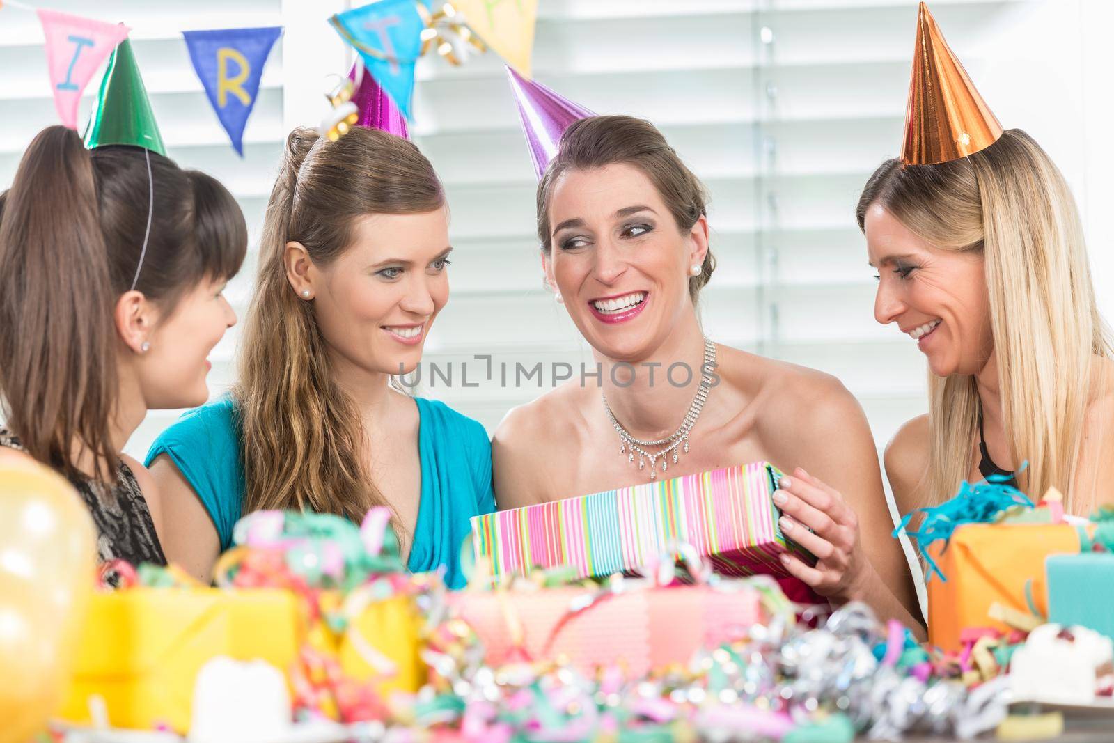 Cheerful woman holding a gift box during a surprise birthday party by Kzenon