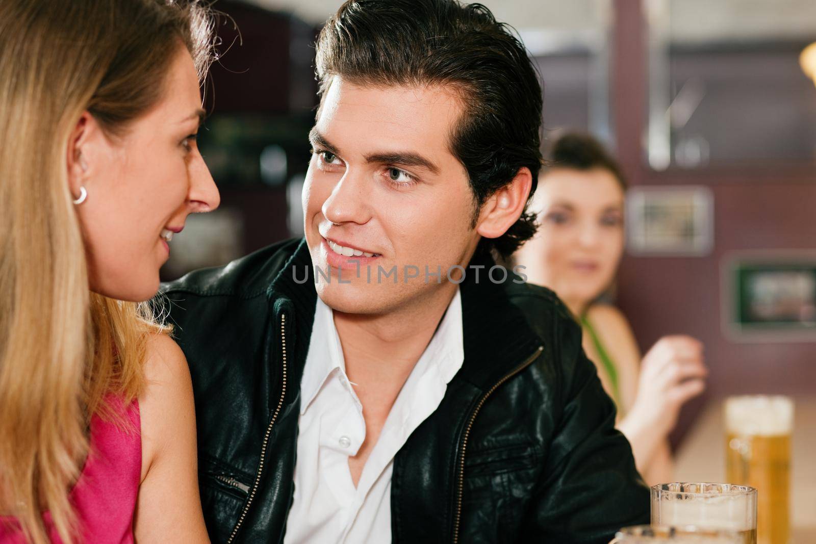 Couple in bar drinking beer flirting by Kzenon