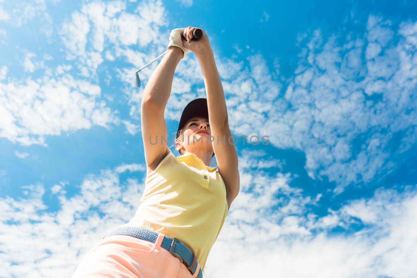 Female professional player holding up the iron club while playing golf by Kzenon
