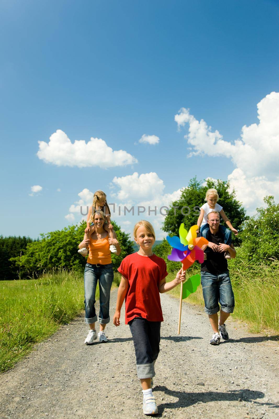 Family having a walk down a path on a sunny day under a perfect blue sky (focus is only on the girl in front!)