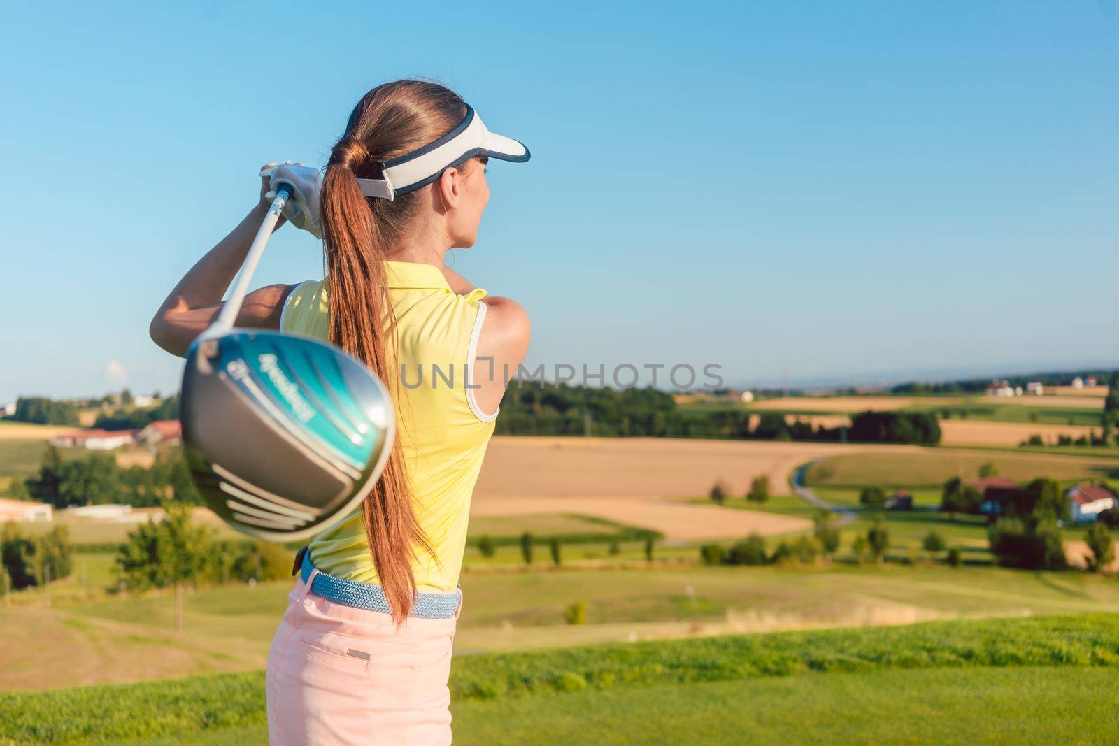 Young woman holding a driver club during golf swing at the begin by Kzenon