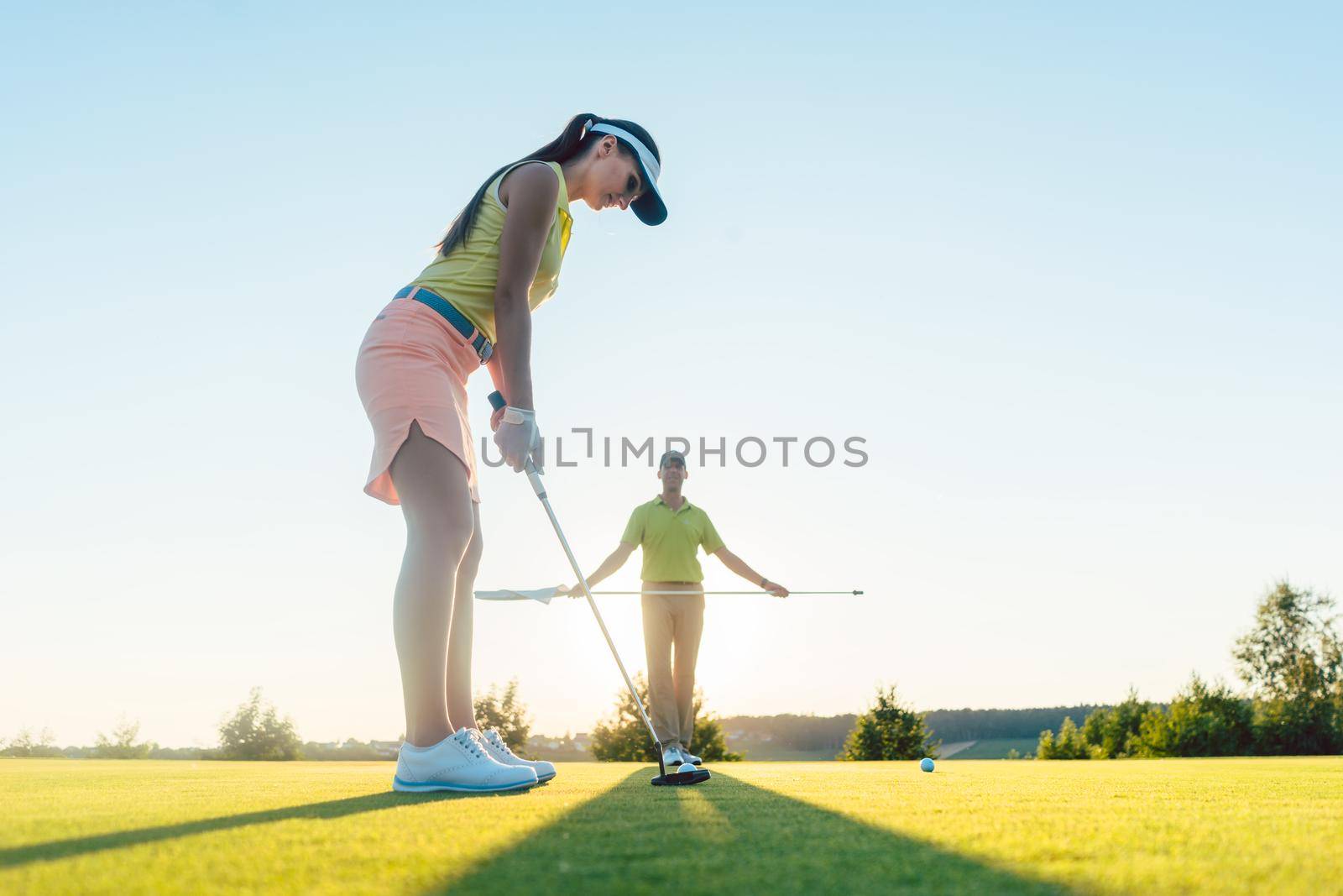 Fit woman exercising hitting technique during golf class with by Kzenon