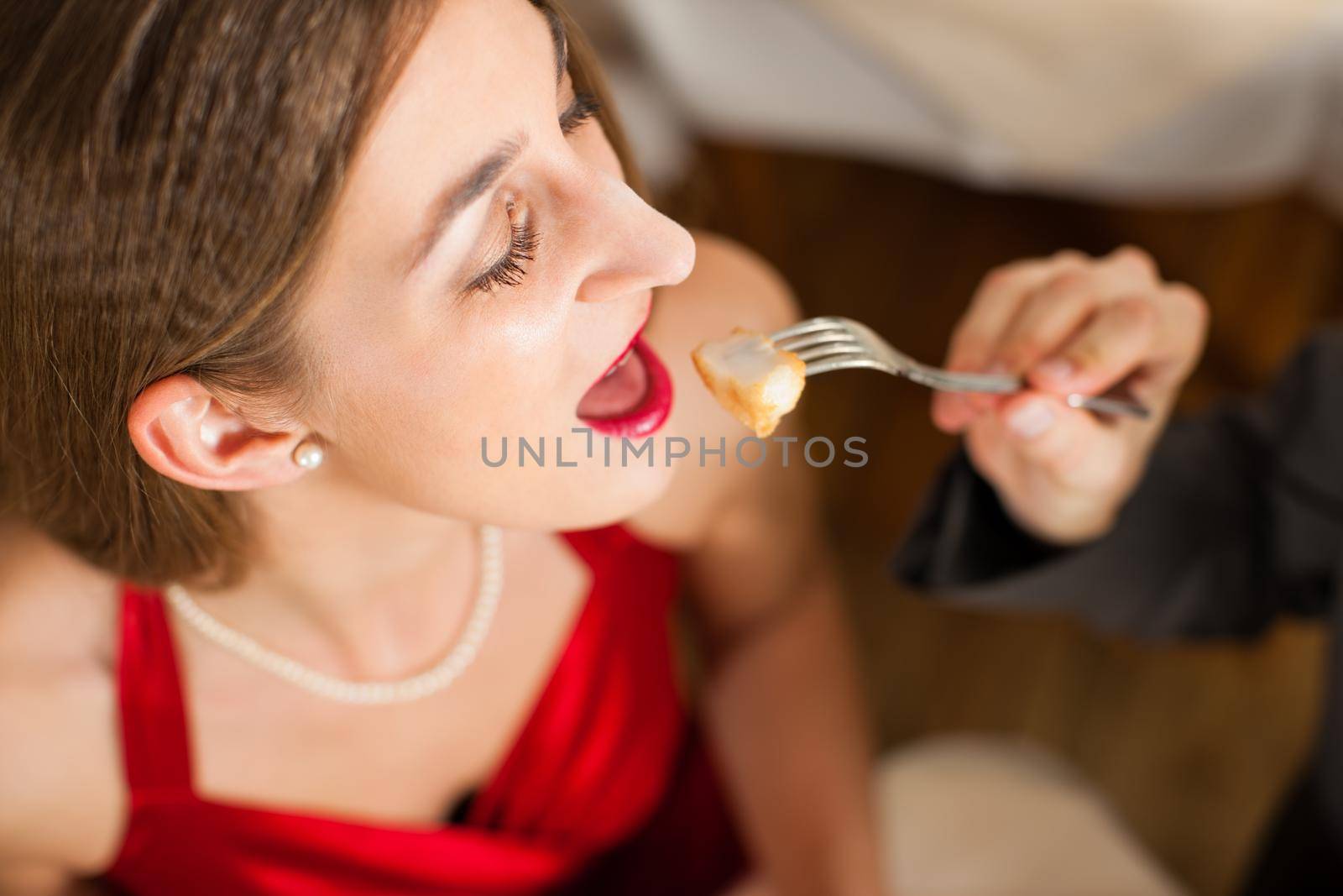 High angle view of man feeding his girlfriend a piece of food