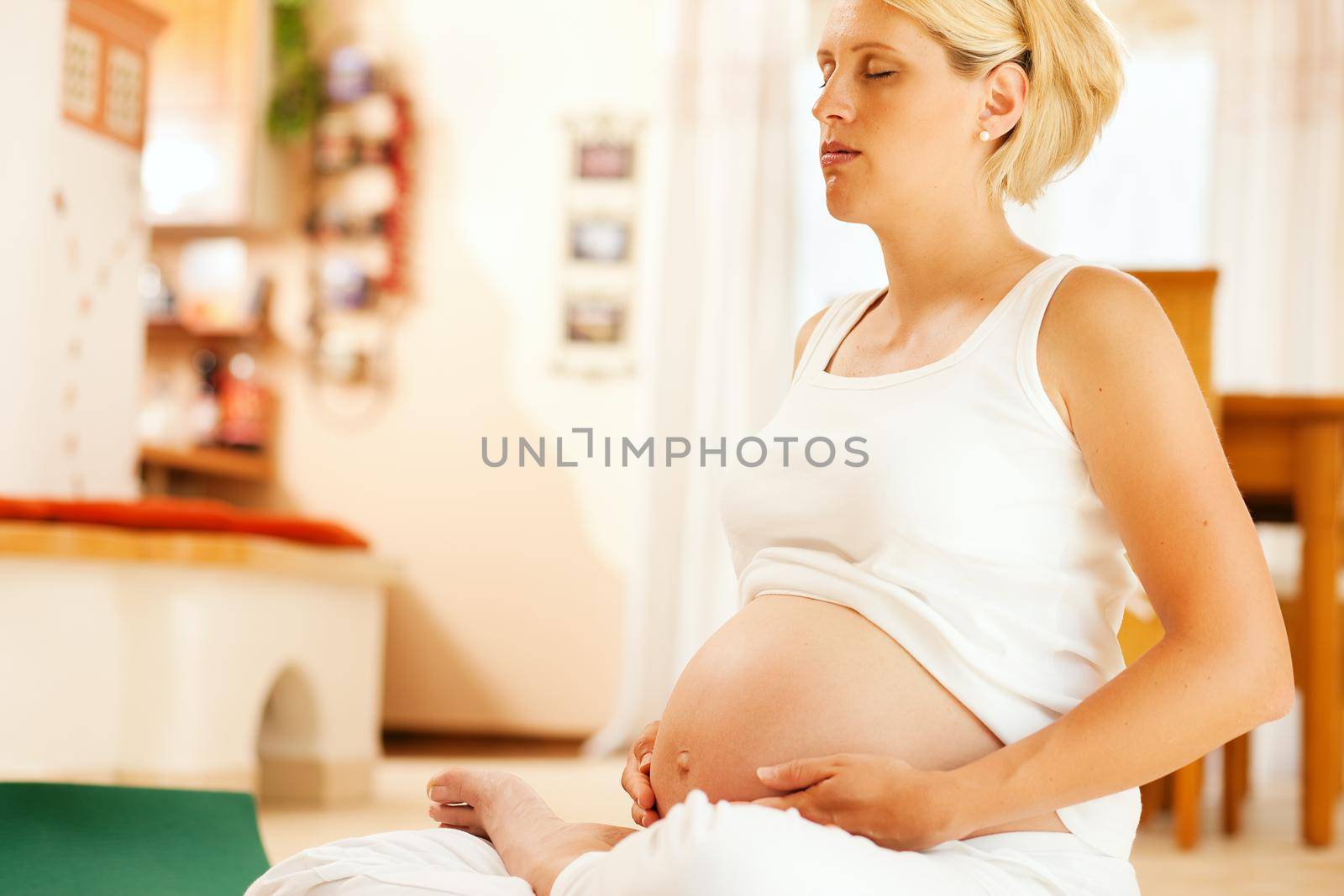 Pregnant woman meditating doing pregnancy yoga sitting on the floor in her home