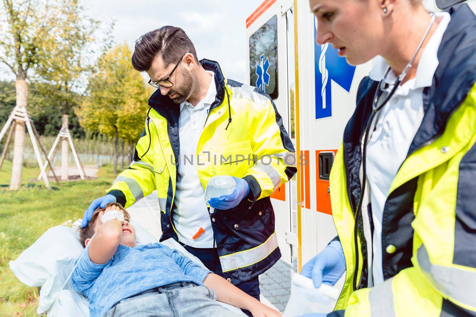 Paramedic and emergency doctor caring for injured boy on stretcher