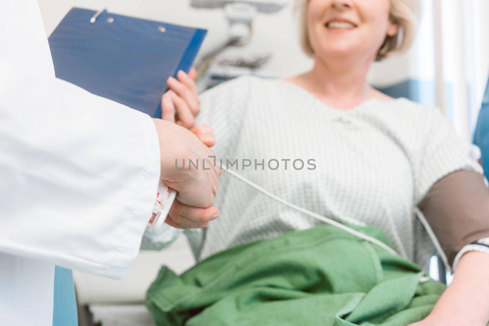 Doctor shaking hands of woman patient recovering after operation in hospital