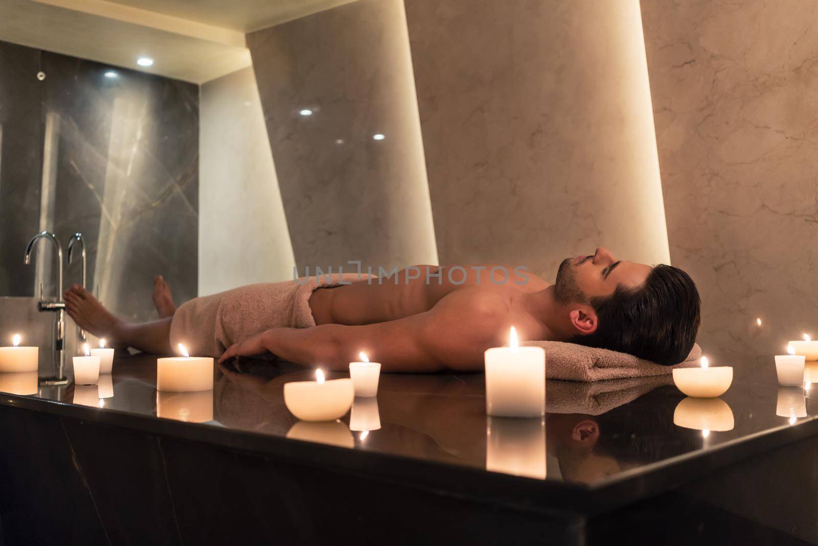 Man relaxing on massage table at Asian spa and wellness center by Kzenon