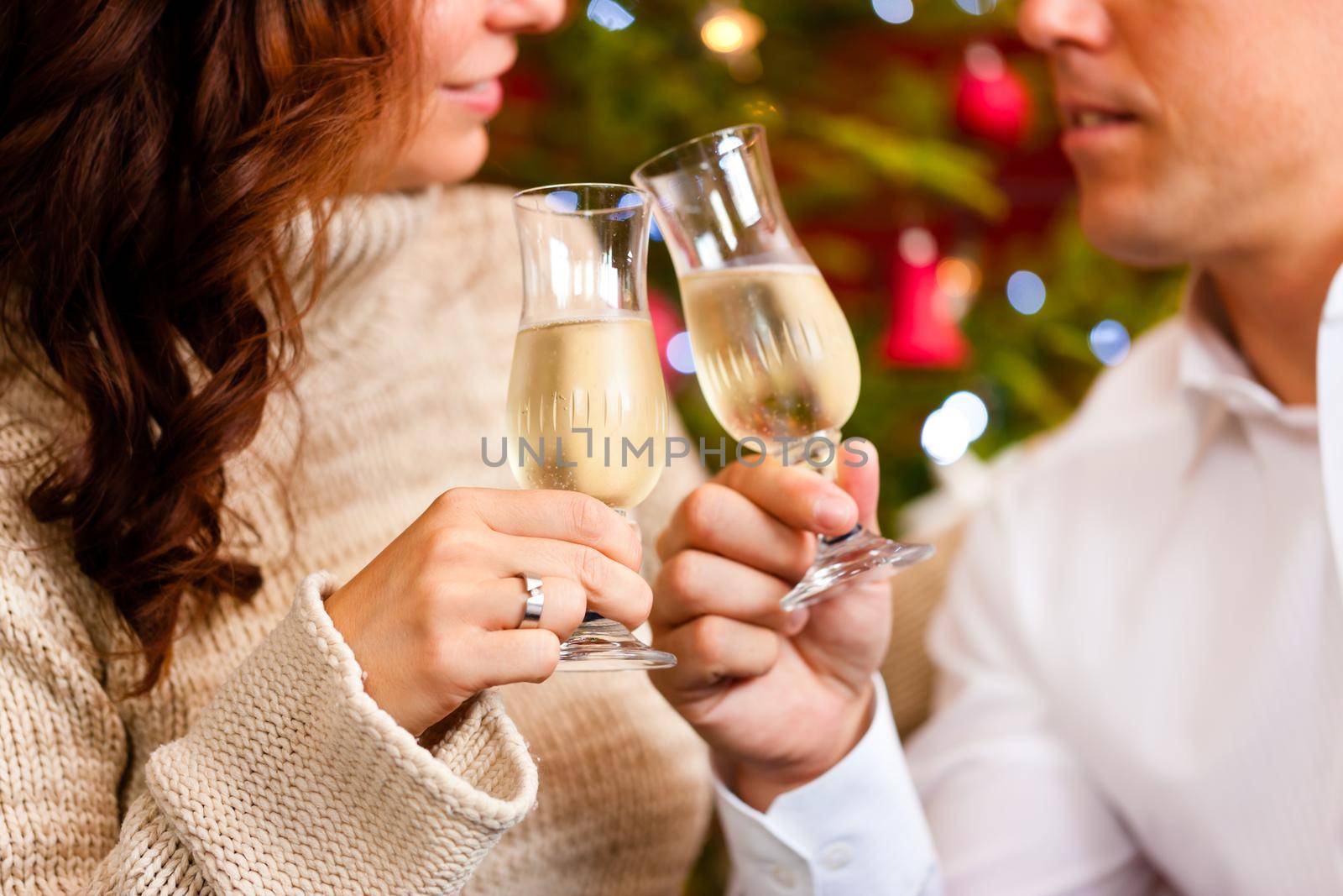 Couple clinking glasses with champagne on Christmas Eve and giving gifts to each other