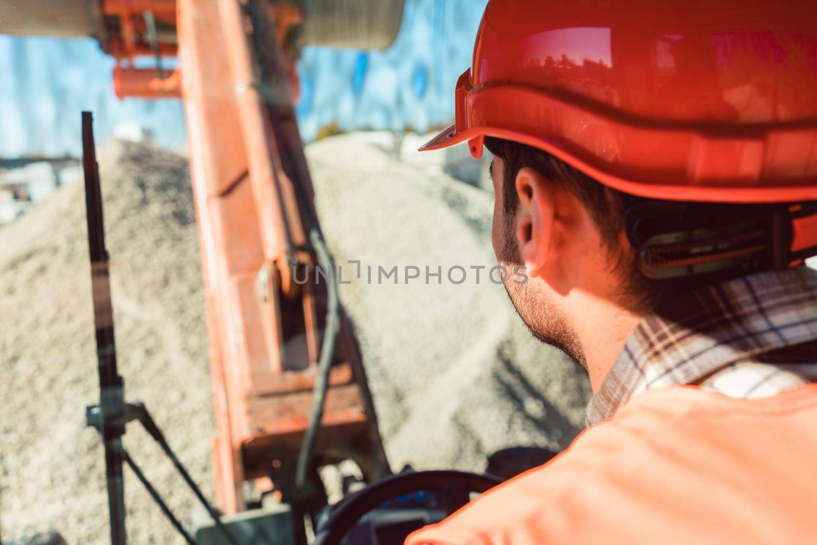 Worker on construction site operating wheel loader by Kzenon