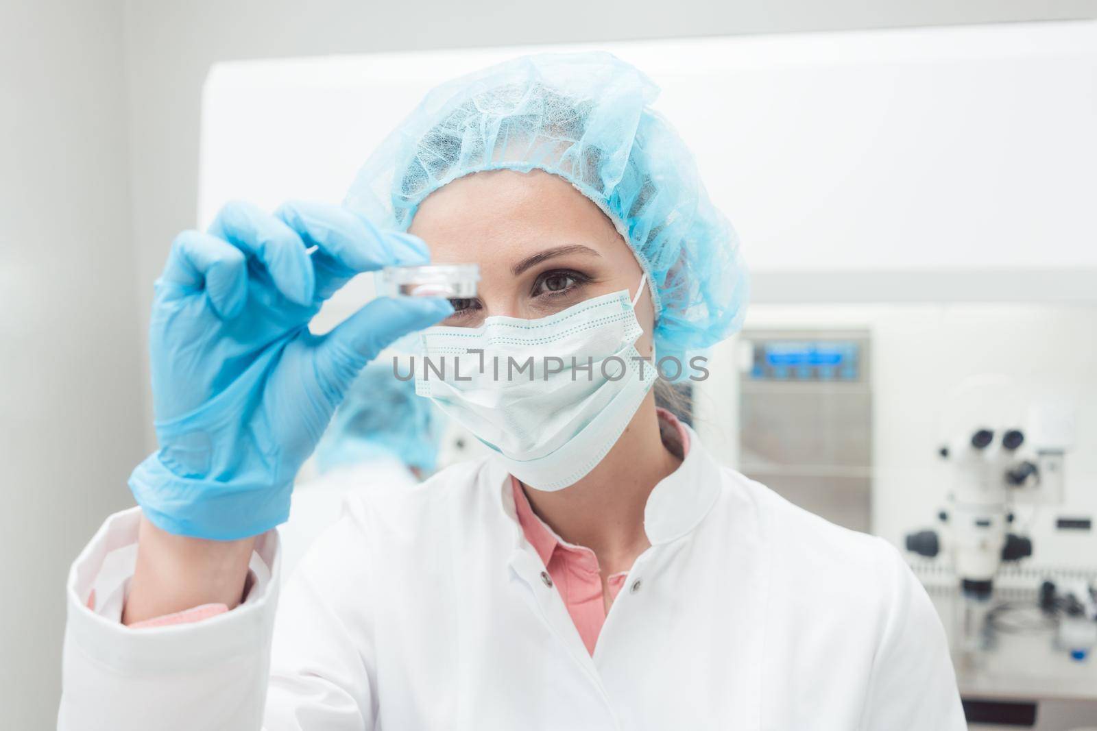 Woman scientist showing her newest biotech experiment in lab petri dish