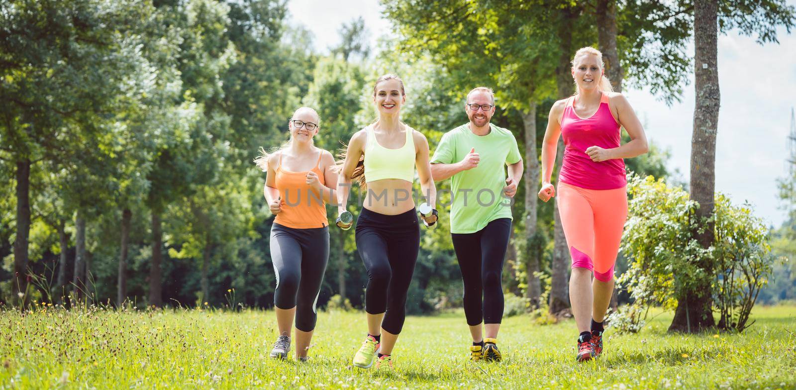 Family with personal Fitness Trainer jogging on a meadow