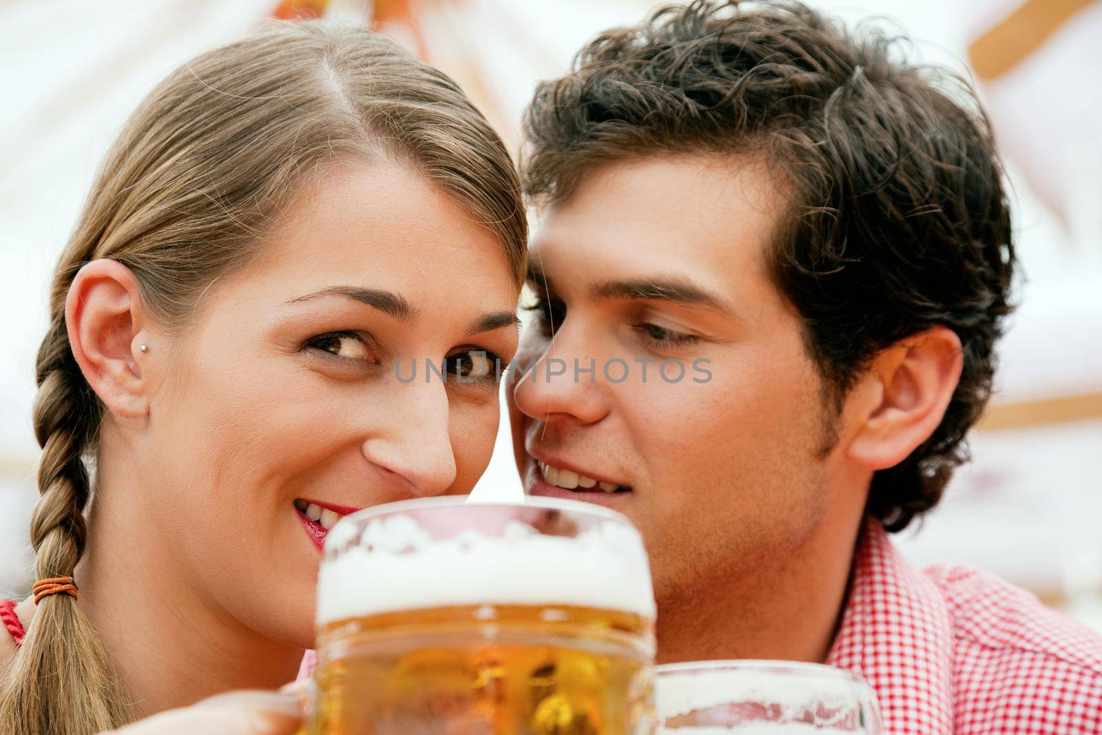 Couple in traditional German costume in a beer tent having a drink, scene could be located at the Oktoberfest or any Dult