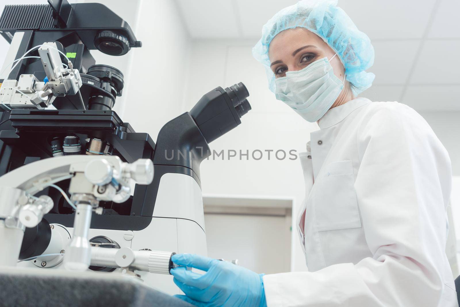 Woman doctor working in medical lab with manipulator and microscope