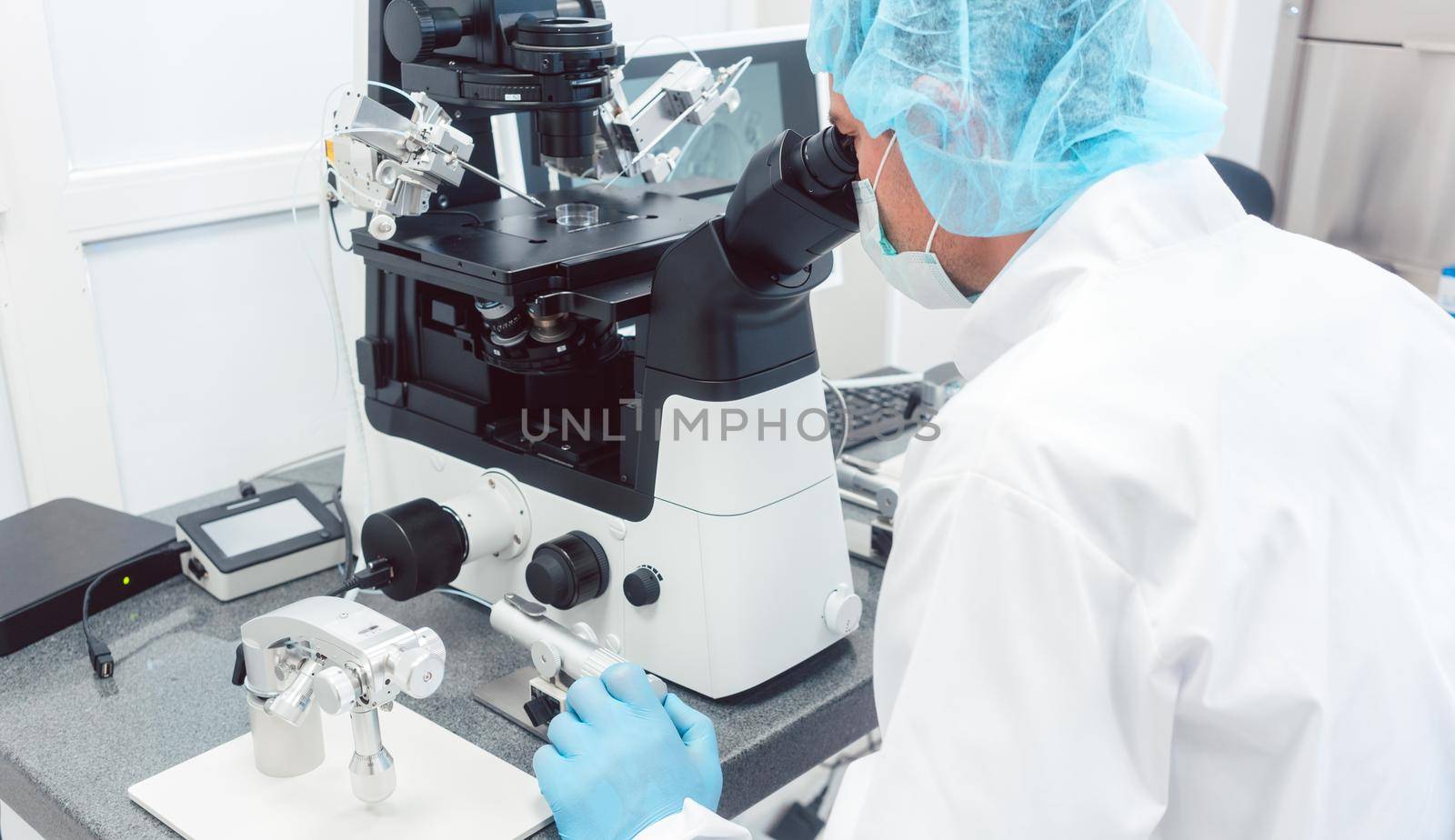 Doctor or scientist looking thru microscope in biotech lab