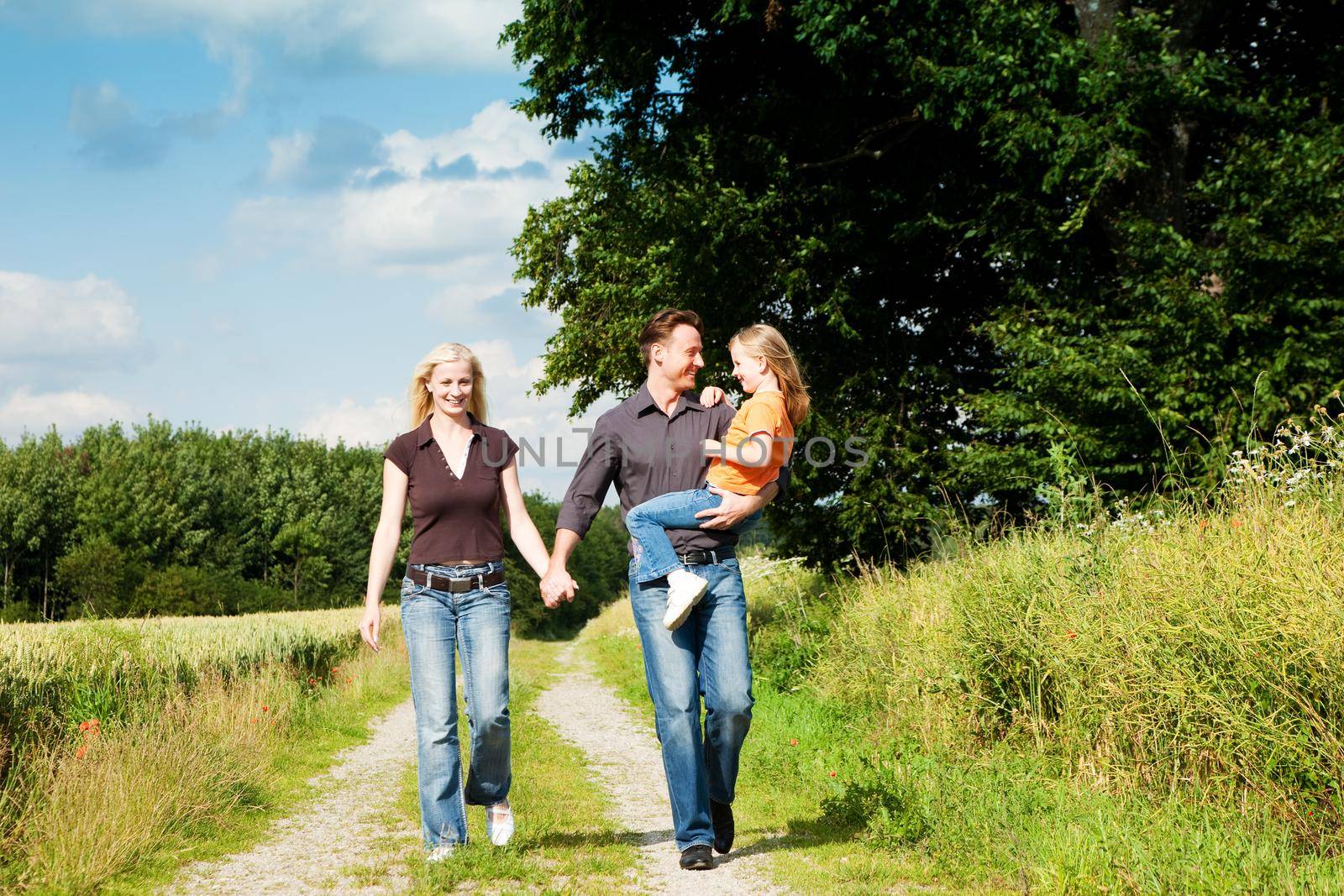 Happy family (mother, father and kid) having a walk in the nature