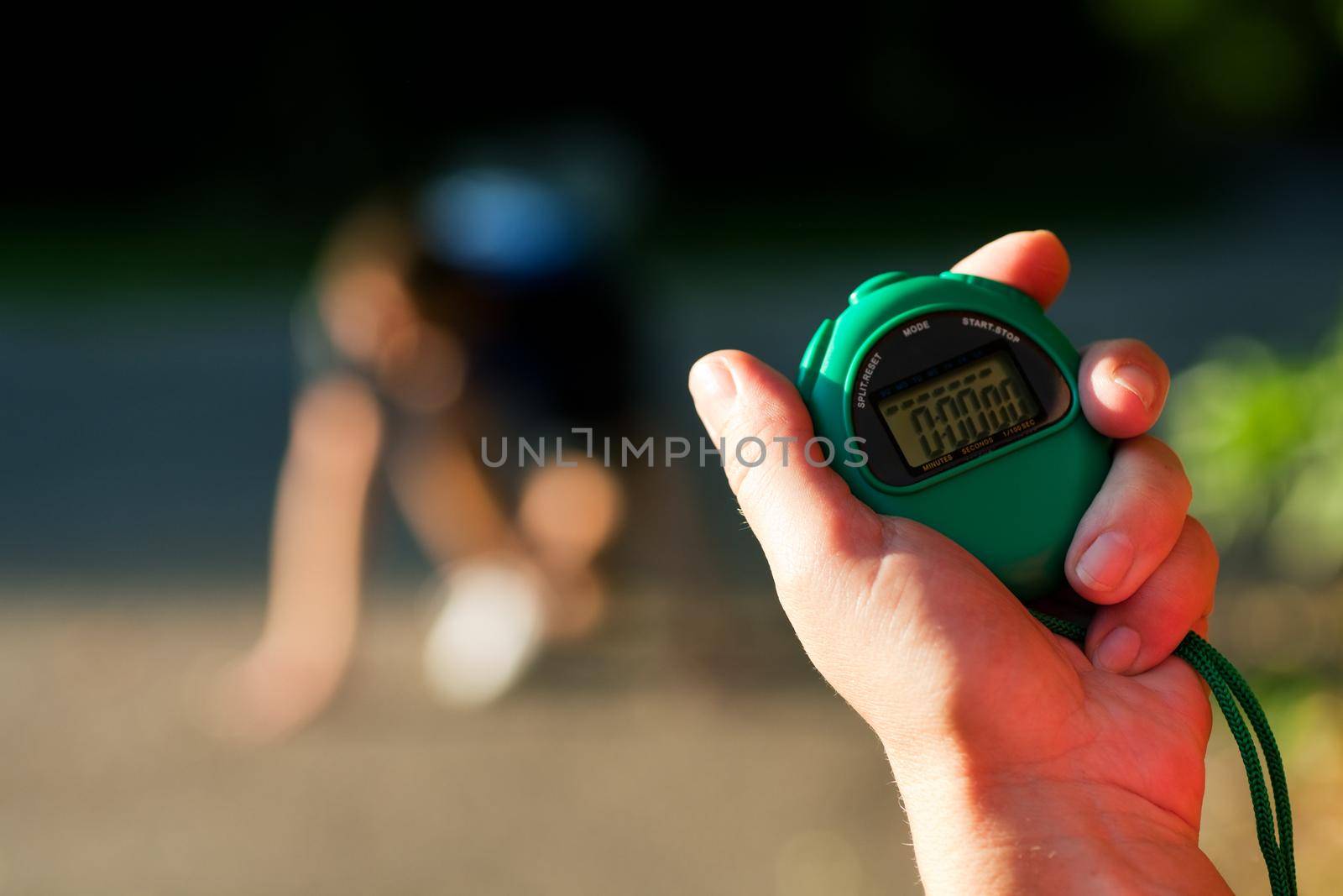 Young man doing sport outdoors, attempting to run or sprint waiting for the start signal, a trainer is ready to measure his performance