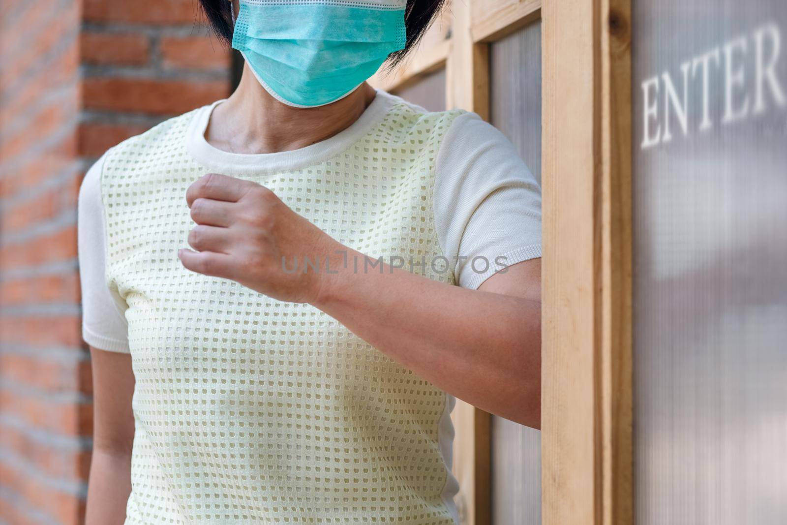 Woman wearing mask opening the door with the elbow for protection  infection COVID-19 by toa55