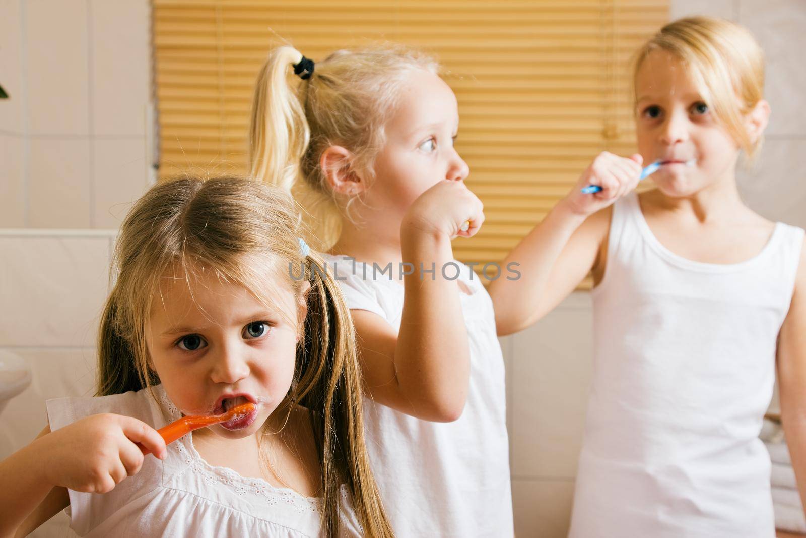Three children - sisters - brushing their teeth