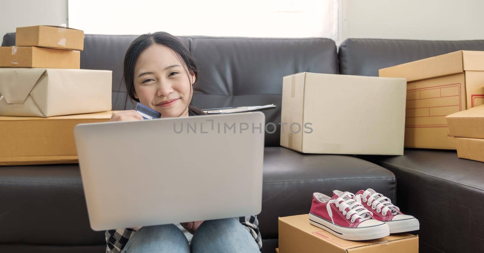 Happy young woman using credit card for online shopping with laptop computer by nateemee