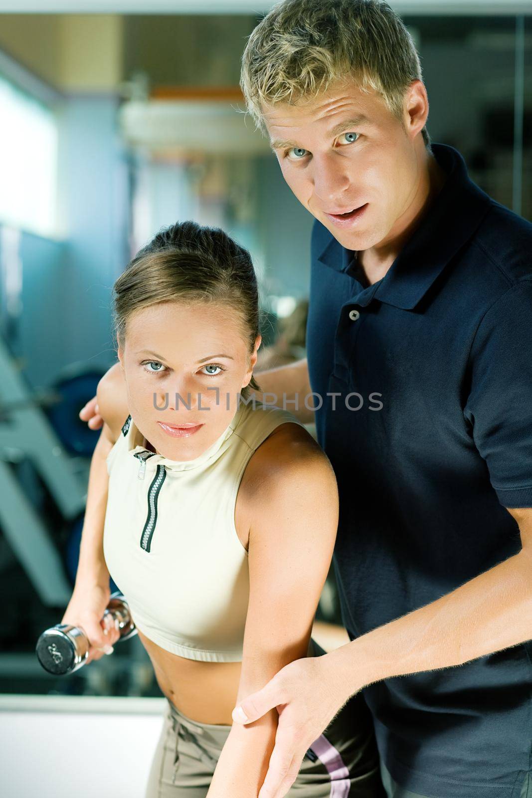 Trainer instructing a beautiful woman in the gym on how to properly exercise