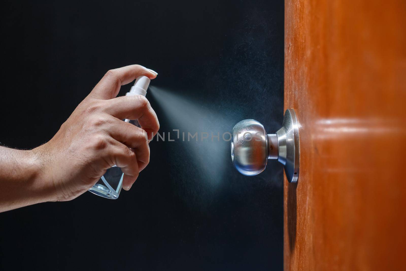 Cleaning door knob with alcohol spray for  Covid-19 (Coronavirus) prevention.